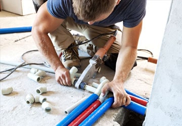 Professional plumber joining pipes on the ground